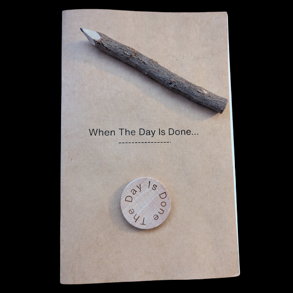 Kraft paper booklet titled “When The Day Is Done…” with a wooden coin and a natural wood pencil placed on top.
